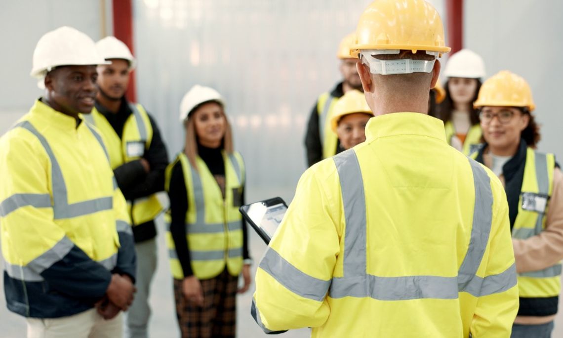 The Importance of Refresher Training for Construction Crews Seven employees on a construction site looking at a site manager who is speaking to the entire group.