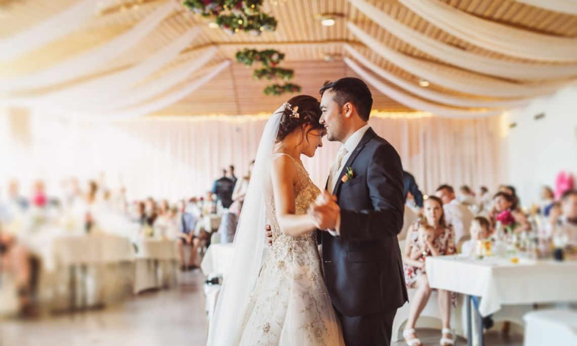 Tips for Deciding Your Wedding Venue Size A bride and groom dancing on the dance floor in a large wedding venue. The guests sit at their tables.