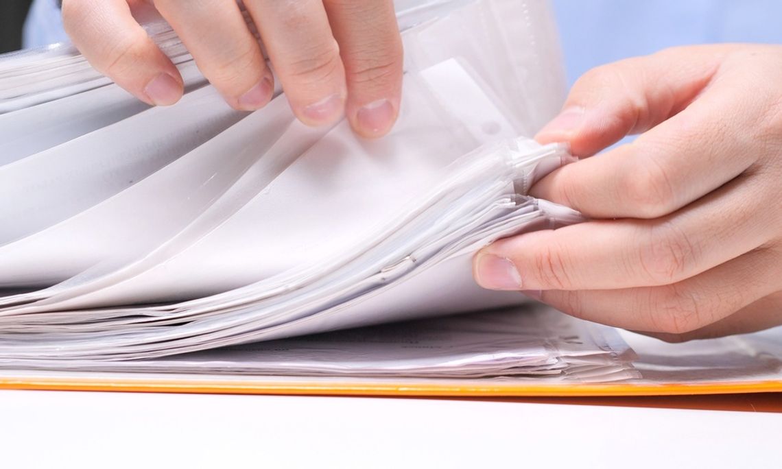 Close-up of a person's fingers flipping through various documents that are in clear plastic sleeves.