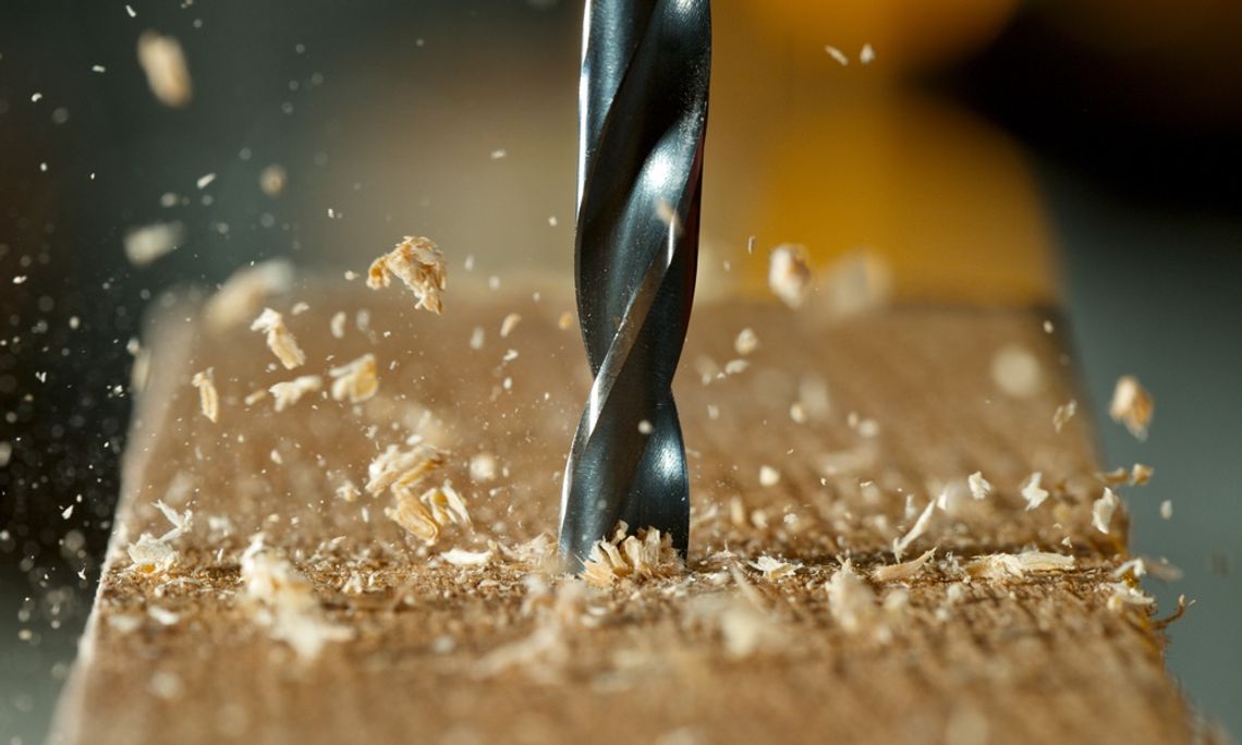 Understanding the Importance of Sharp Drill Bits Close-up of a sharp drill bit boring into a wooden board as wood shavings and sawdust scatter through the air.