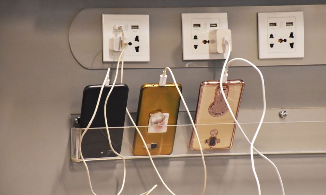 Unexpected Amenities That Make Customers Feel Seen Three smartphones connected to charging cables at a public charging station with multiple electrical outlets.