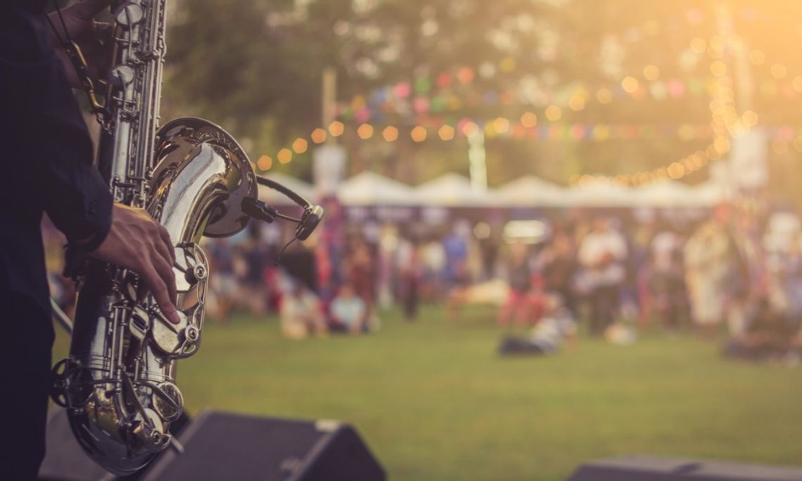 What To Wear to Outdoor Events in Mississippi A saxophone player performs onstage as people gather across a grassy field during a sunny outdoor festival.