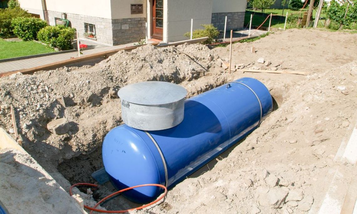 A tank that is underground and surrounded by a pile of dirt. The tank is blue, and there's a cord near it.